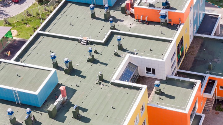 Top view flat roof with air conditioners and hydro insulation membranes on top of a modern apartment.